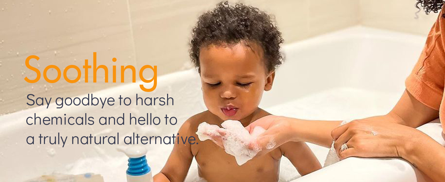 Baby boy in bath tub blowing bath bubbles from mother's hand